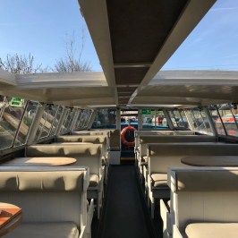 Interior of an empty boat with booth seating, tables, and a life preserver.