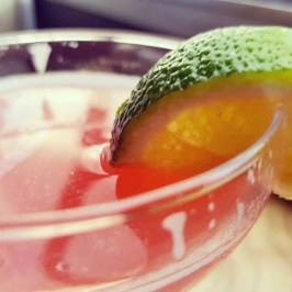 Close-up of a cocktail in a glass with a lime wedge on the rim.