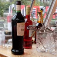 Bottles of wine and glasses on a wooden countertop near a window.