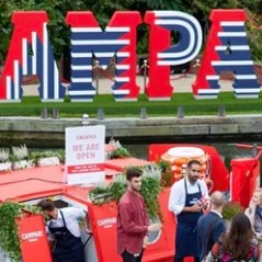 Campari barge on a canal with staff and visitors, large CAMPA letters in the background.