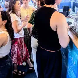 People gathered at a bar under string lights, engaging in conversation.